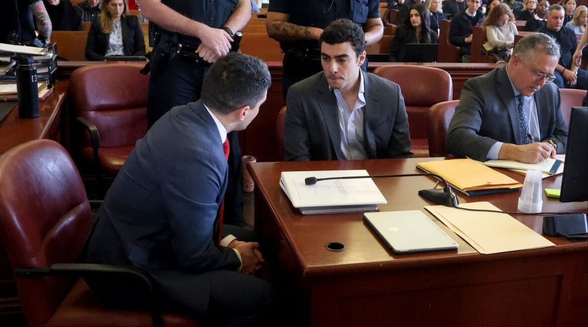 Luigi Mangione, seated second from left, confers with one of his attorneys as he awaits the start of a pretrial hearing in State Supreme Court in Manhattan on Thursday morning, Dec. 11, 2025. Lawyers for Luigi Mangione asked a federal judge on Wednesday, March 18, 2026, to push his murder trial back until early next year, arguing that they cannot prepare for a separate state trial at the same time. (Jefferson Siegel/The New York Times)