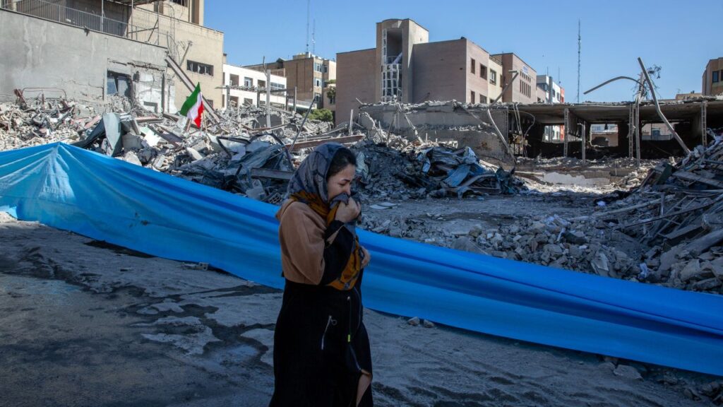 Image of a woman walking past a flattened police station hit by US-Israeli airstrikes in Tehran, Iran