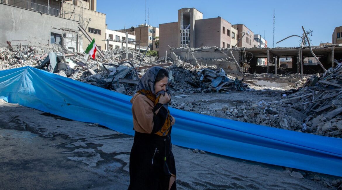 Image of a woman walking past a flattened police station hit by US-Israeli airstrikes in Tehran, Iran
