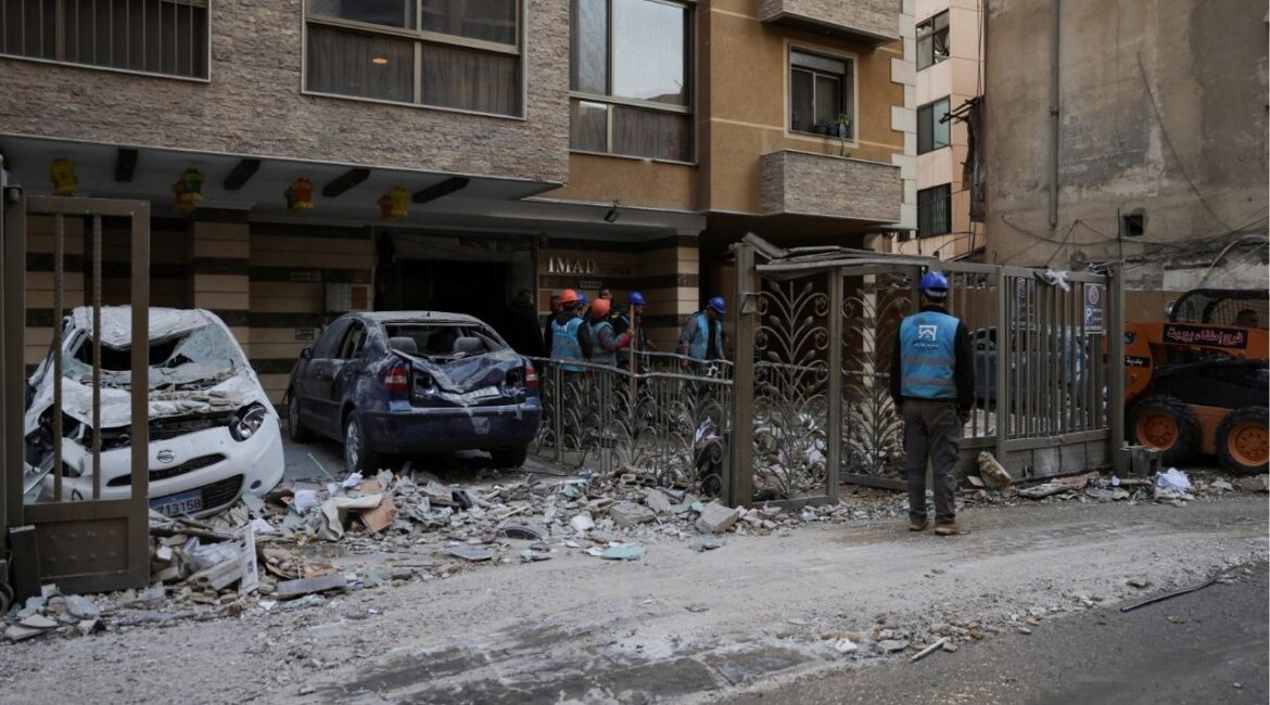 People stand near debris and damaged vehicles at the site of an Israeli strike on an apartment building, in central Beirut, Lebanon, March 11, 2026, following an escalation between Hezbollah and Israel amid the U.S.-Israeli conflict with Iran. (Reuters/Emilie Madi)