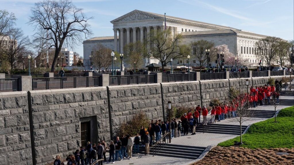 People wait in line to visit the U.S. Capitol with the Supreme Court building behind them in Washington, on Tuesday, March 24, 2026. The Supreme Court on Tuesday is set to hear a case that will determine whether the Trump administration can turn away asylum seekers along the U.S.-Mexico border. (Eric Lee/The New York Times)