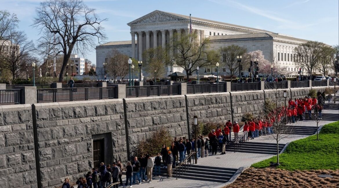 People wait in line to visit the U.S. Capitol with the Supreme Court building behind them in Washington, on Tuesday, March 24, 2026. The Supreme Court on Tuesday is set to hear a case that will determine whether the Trump administration can turn away asylum seekers along the U.S.-Mexico border. (Eric Lee/The New York Times)