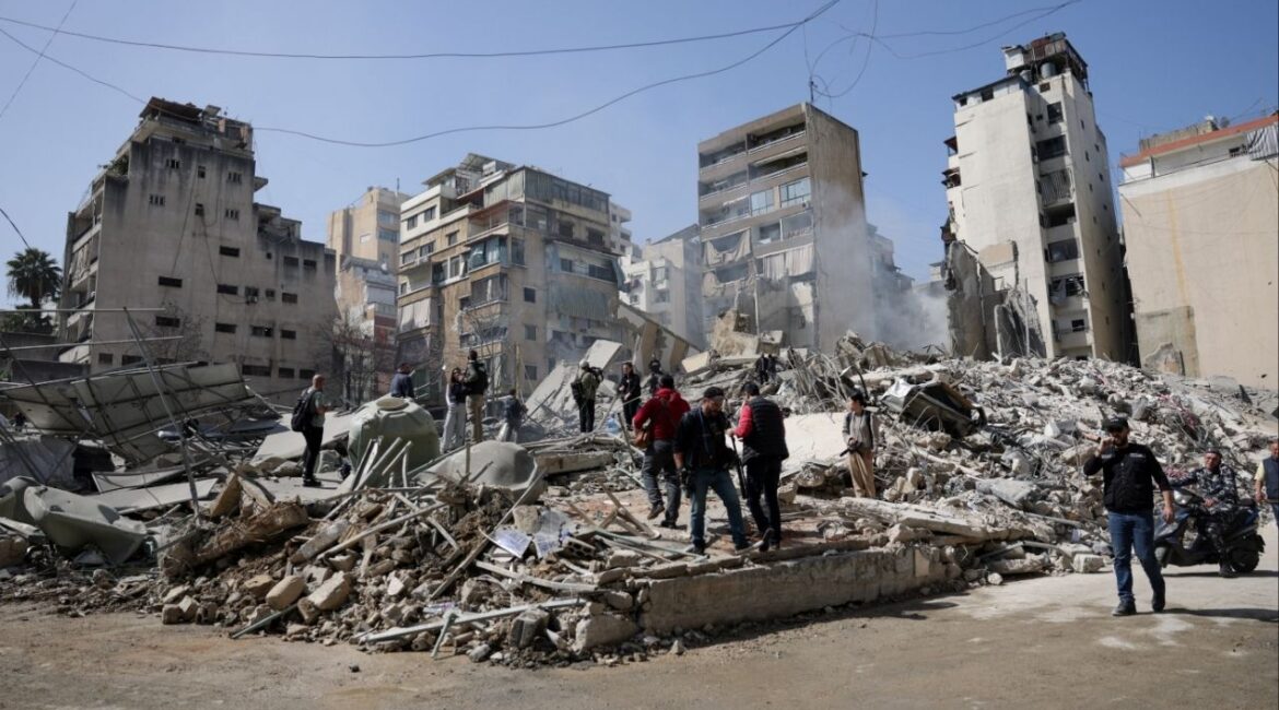 People walk amidst debris at the site of an Israeli strike, following an escalation between Hezbollah and Israel amid the U.S.-Israeli conflict with Iran, Zuqaq al-Blat district in central Beirut, Lebanon, March 18, 2026. (Reuters/Khalil Ashawi)