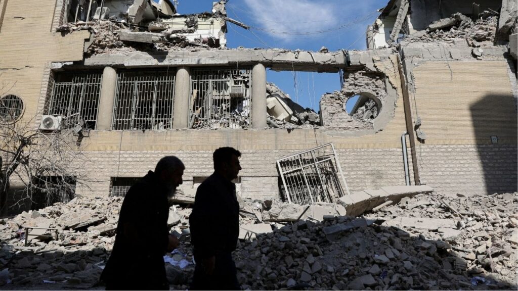 People walk past damaged buildings following a strike on a police station, amid the U.S.-Israeli conflict with Iran, in Tehran, Iran, March 4, 2026. (Majid Asgaripour/WANA (West Asia News Agency) via Reuters)