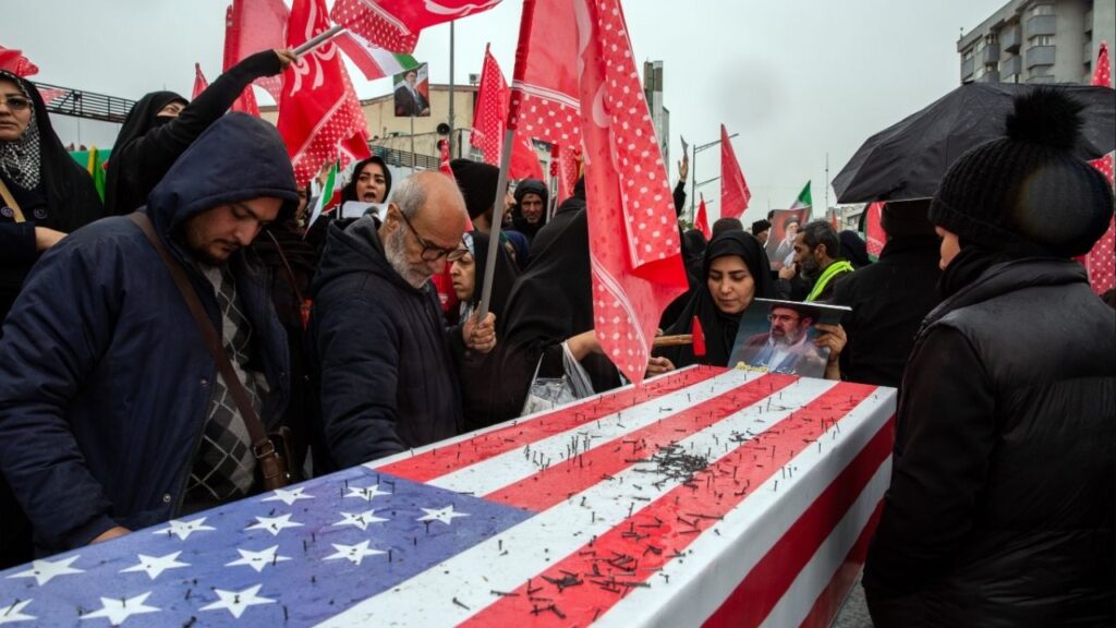 Supporters of the Iranian government hammer nails into a coffin draped with a United States flag during a rally in Tehran marking Quds Day, an event held annually by the Iranian government to oppose Israel, on the last Friday of Ramadan, March 13, 2026. An explosion was seen on Friday close to where crowds had gathered in Tehran for a rally, according to videos shared by Iranian state television. It was not immediately clear what had caused the explosion. (Arash Khamooshi/The New York Times)