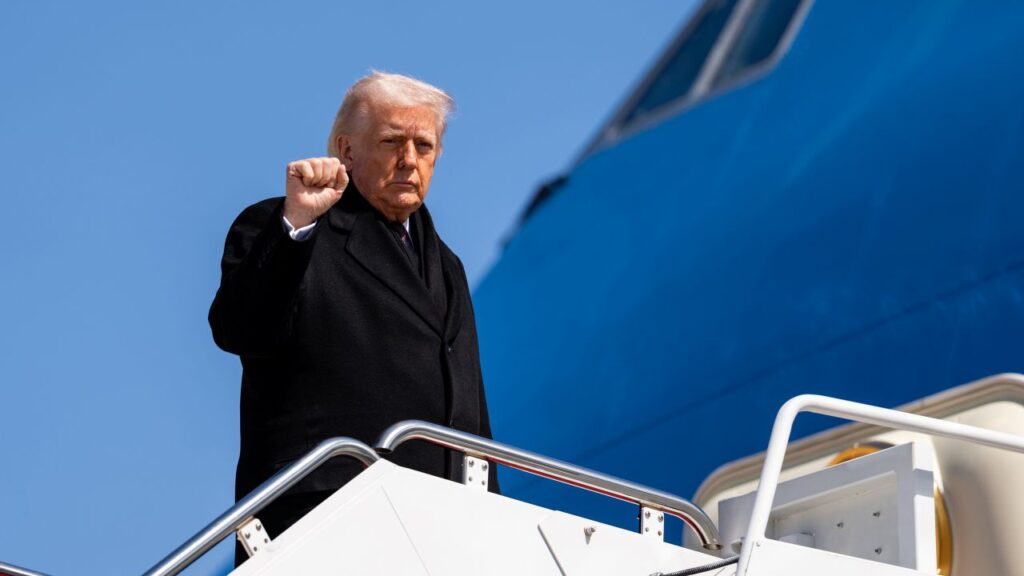 Image of President Trump in a black coat boarding Air Force One