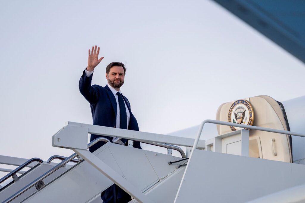 Image of JD Vance in a blue suit waving as he boards Air Force Two