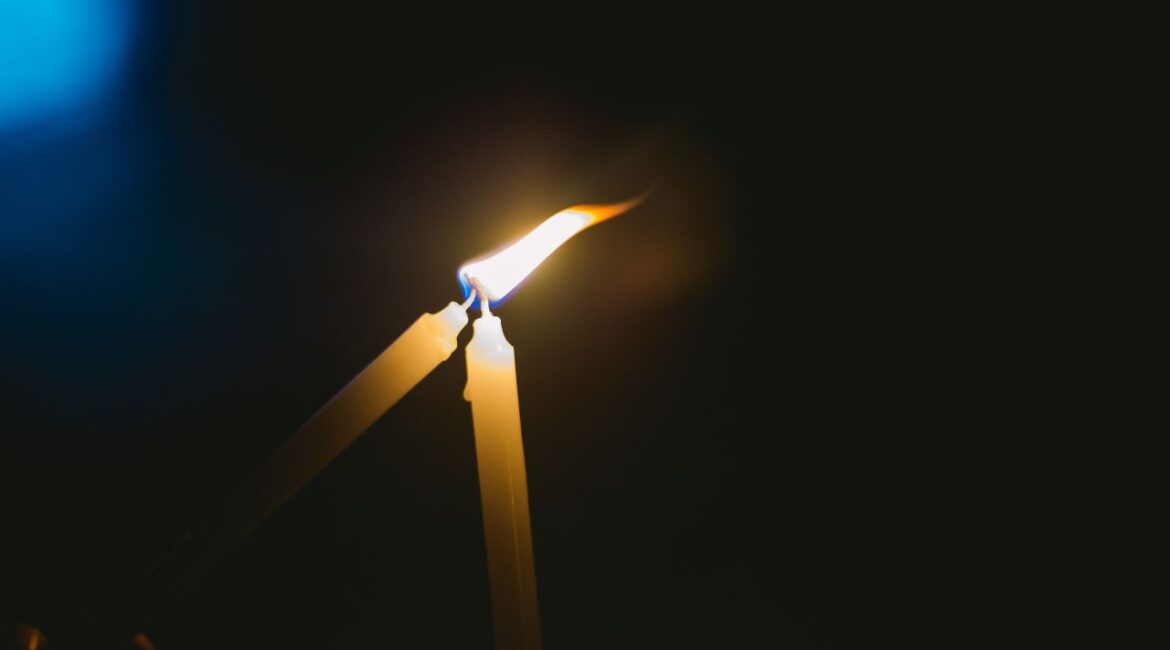 Image of a candle lighting another candle at night