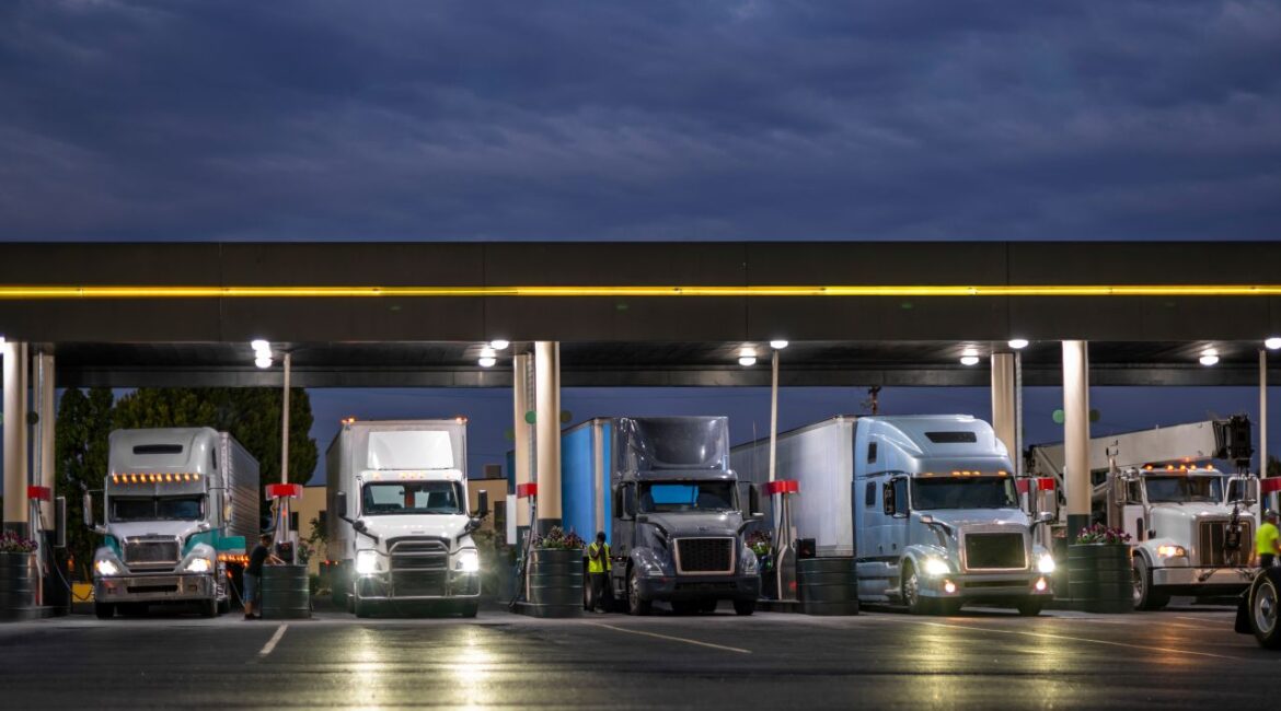 Image of transport trucks lined up at night at a fueling station