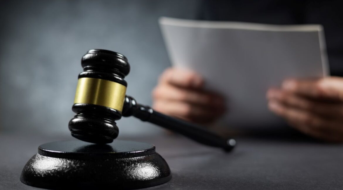 Image of a judge holding documents in front of a black and gold gavel
