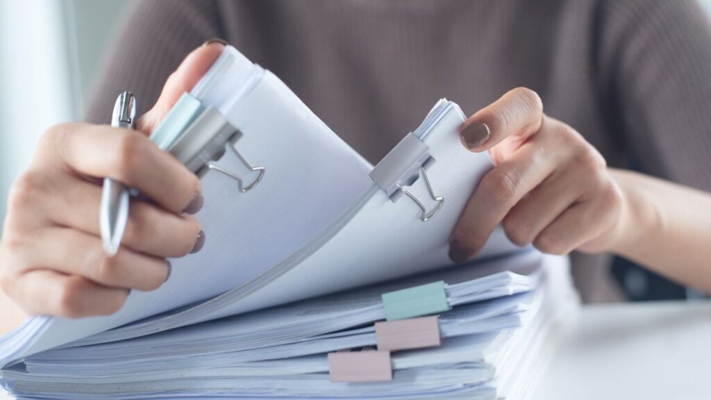 Image of a woman handling a large stack of documents