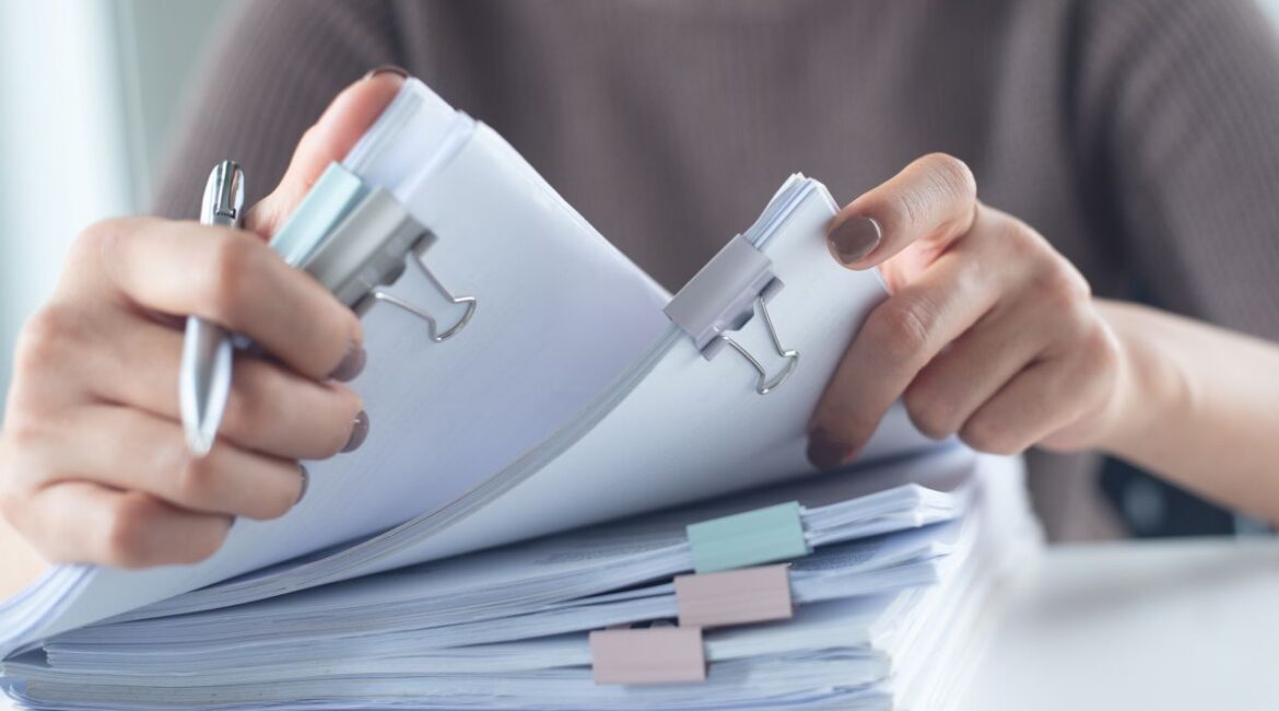 Image of a woman handling a large stack of documents