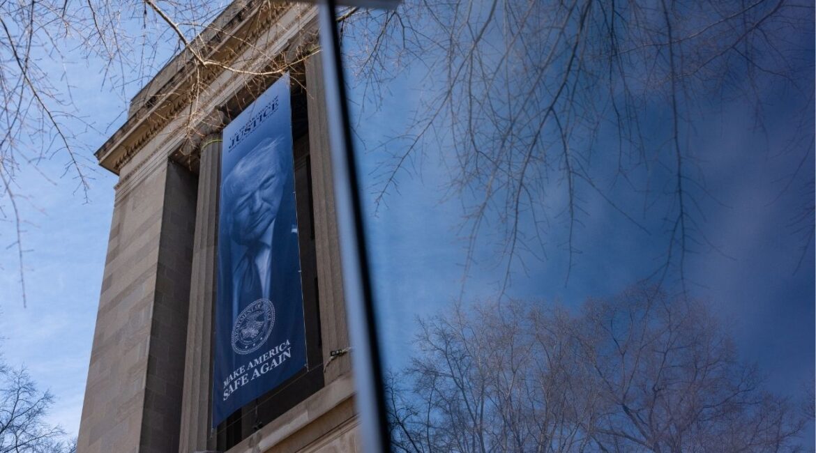 A banner bearing the face of President Donald Trump hangs from the Department of Justice building in Washington, Feb. 20, 2026. The Southern Poverty Law Center, a civil rights group, said on Tuesday that it was under investigation by the Justice Department over its past use of paid informants to infiltrate extremist groups. (Eric Lee/The New York Times)