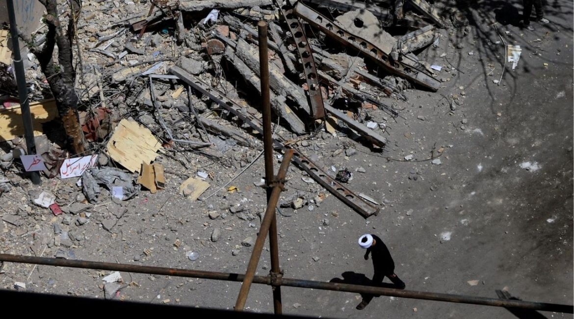 A cleric walks near a residential building damaged by a strike on March 4, in Tehran, Iran, April 14, 2026. (Reuters/Thaier Al Sudani)