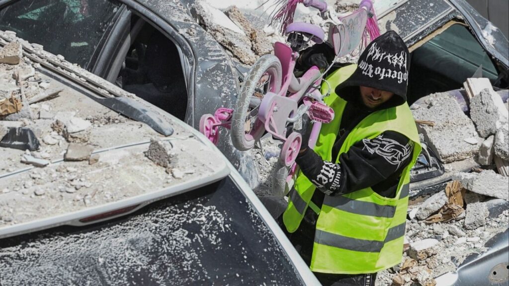 A man wearing a high-visibility vest carries a child's bicycle at an impact site, following a barrage of missiles launched from Iran, amid the U.S.-Israeli conflict with Iran, in central Israel, April 6, 2026. (Reuters/Nir Elias)