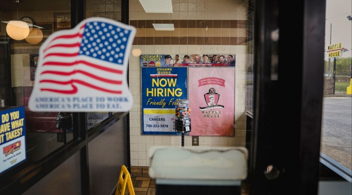 A view through a glass doorway at the Waffle House on Martha Berry Highway in Rome, Ga., April 2, 2026. Gregg Phillips, the Federal Emergency Management Agency (FEMA) official in charge of responding to fires and floods, says the hand of God suddenly and mysteriously moved him to the 24-hour breakfast spot. (Nicole Craine/The New York Times)