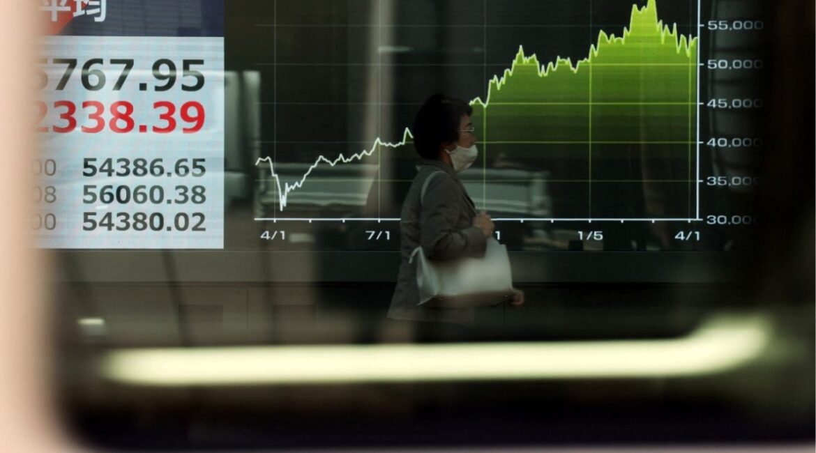 A woman walks past a screen displaying Japan's Nikkei share average and a graph showing recent movements of the average, outside a brokerage in Tokyo, Japan April 8, 2026. (Reuters/Issei Kato)