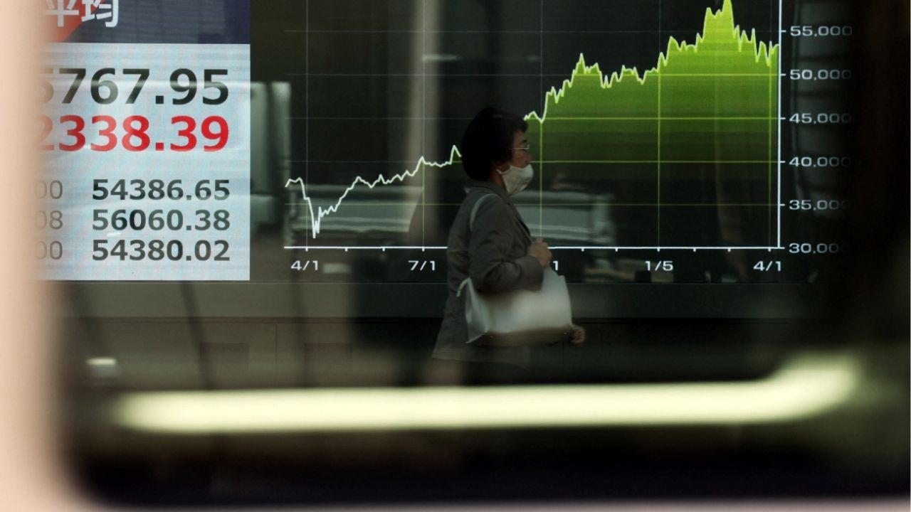 A woman walks past a screen displaying Japan's Nikkei share average and a graph showing recent movements of the average, outside a brokerage in Tokyo, Japan April 8, 2026. (Reuters/Issei Kato)