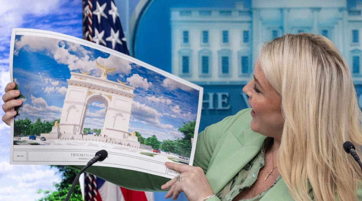 Karoline Leavitt in a pastel green suit looks at the Triumphal Arch rendering during a briefing