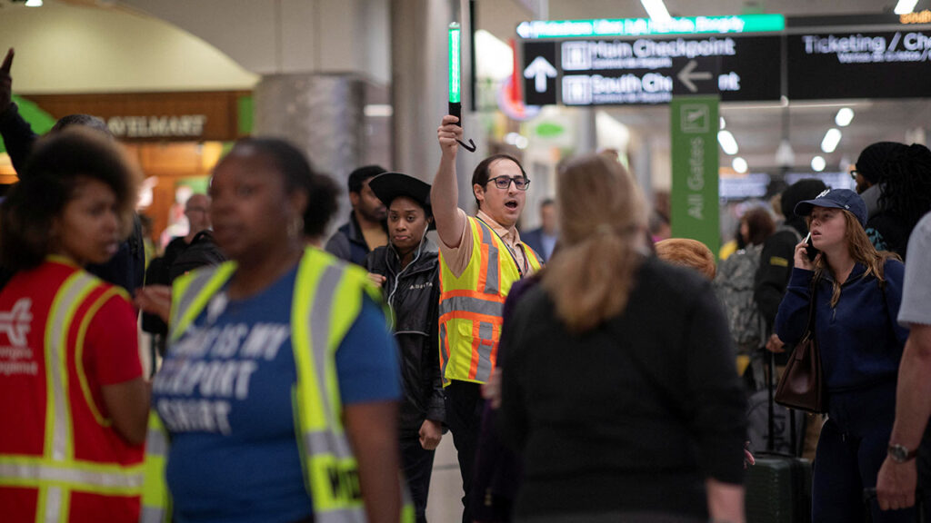 A Hartsfield-Jackson Atlanta International Airport employee directs traffic inside the domestic terminal as passengers stand in long lines to access a Transportation Security Administration (TSA) checkpoint at Hartsfield-Jackson Atlanta International Airport in Atlanta, Georgia, U.S. March 27, 2026. (Reuters/Alyssa Pointer)