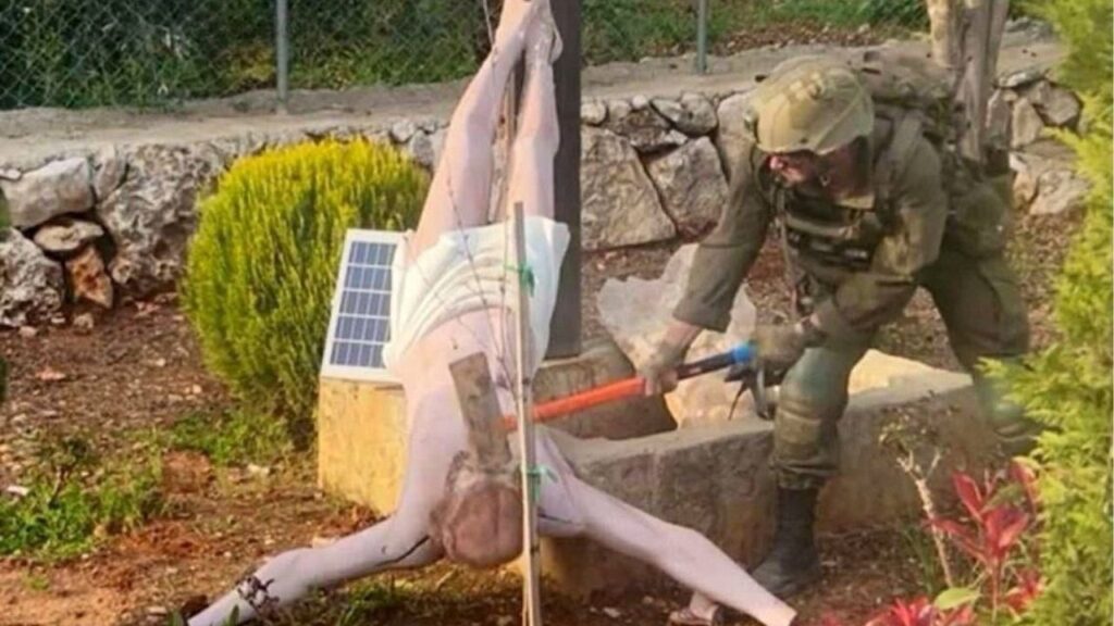 An Israeli soldier damages the head of a statue of Jesus, in Debel, Lebanon, in this still image obtained from social media released on April 19, 2026. Social Media/via REUTERS
