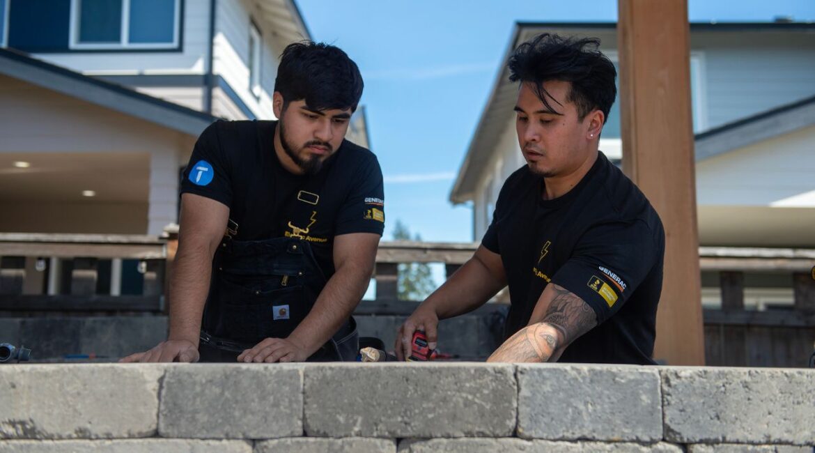 Jack Marquardt, right, of Electric Avenue, works with employee Jonathan Morales installing electricity for an outdoor living space in Happy Valley, Ore., April 6, 2026. Skilled electricians, plumbers and factory workers are in demand, but job openings have dropped. (Amanda Lucier/The New York Times)