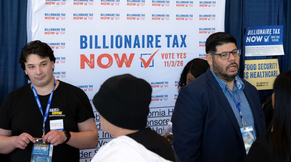 Image of backers of the California billionaires tax standing in front of a poster promoting the ballot initiative