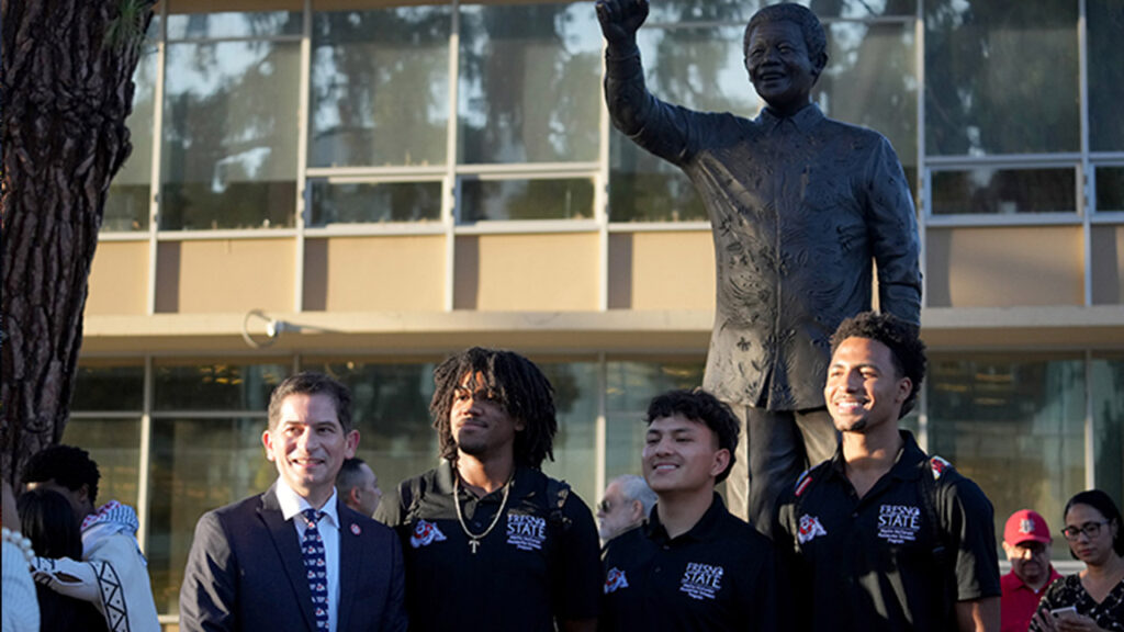 Fresno State President Saúl Jiménez-Sandoval and Fresno State students at the Nelson Mandela monument at the campus Peace Garden