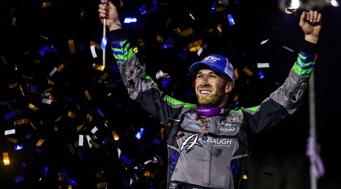 Image of sprint car driver Carson Macedo celebrating a victory. There's confetti falling through the night air.