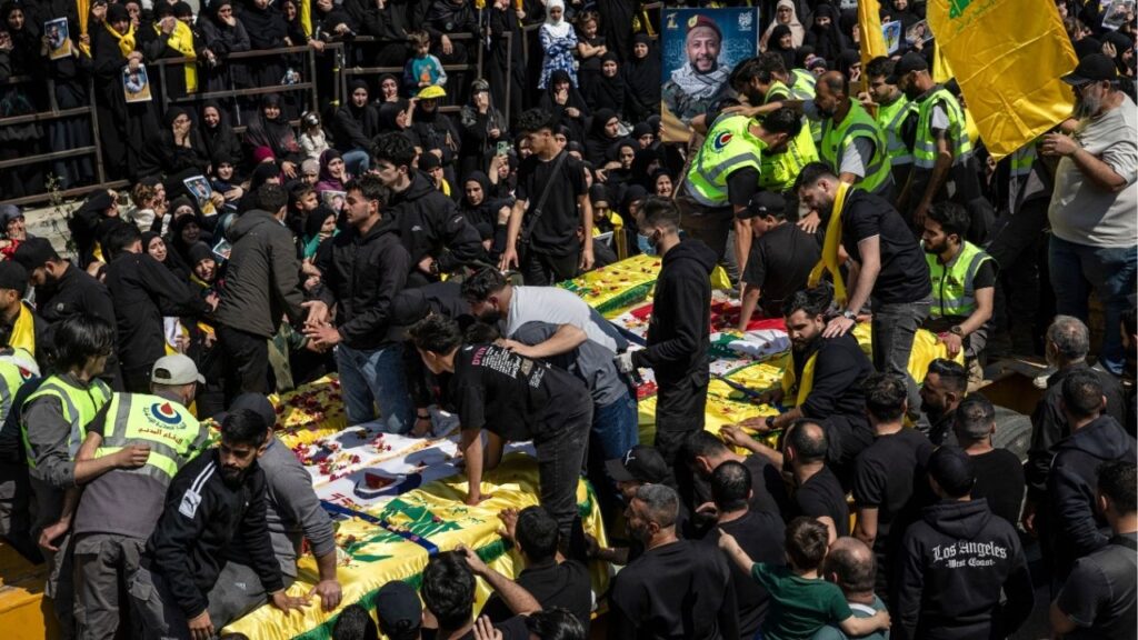 Mourners as a flatbed truck arrives carrying 12 coffins during a mass funeral in the southern Lebanese village of Aytit, on Wednesday, April 22, 2026. Families gathered for the funeral of twelve people who were killed in recent weeks but could not be brought to their home village during the fighting. (David Guttenfelder/The New York Times)