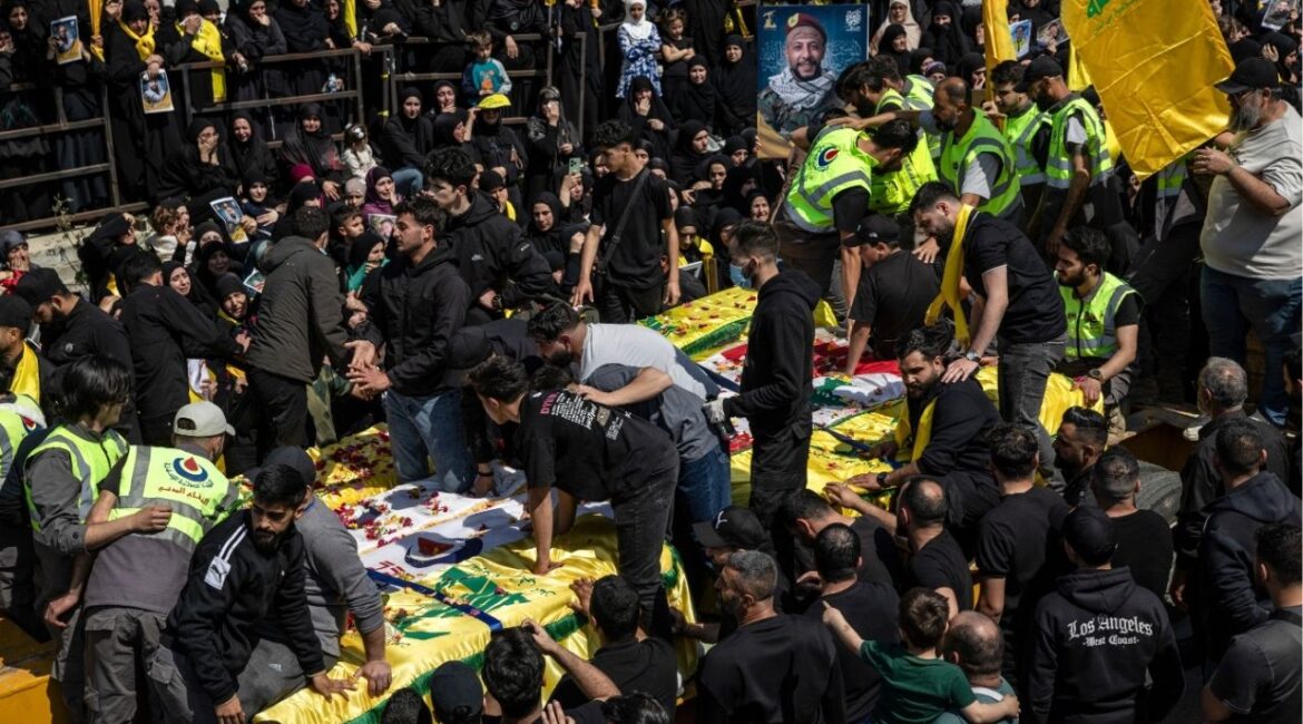Mourners as a flatbed truck arrives carrying 12 coffins during a mass funeral in the southern Lebanese village of Aytit, on Wednesday, April 22, 2026. Families gathered for the funeral of twelve people who were killed in recent weeks but could not be brought to their home village during the fighting. (David Guttenfelder/The New York Times)
