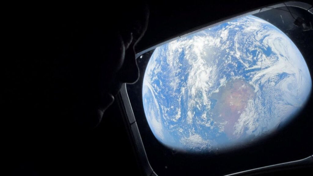 NASA astronaut and Artemis II Commander Reid Wiseman peers out of one of the Orion spacecraft's main cabin windows, looking back at Earth, as the crew travels towards the Moon April 2, 2024. NASA/Handout via REUTERS.