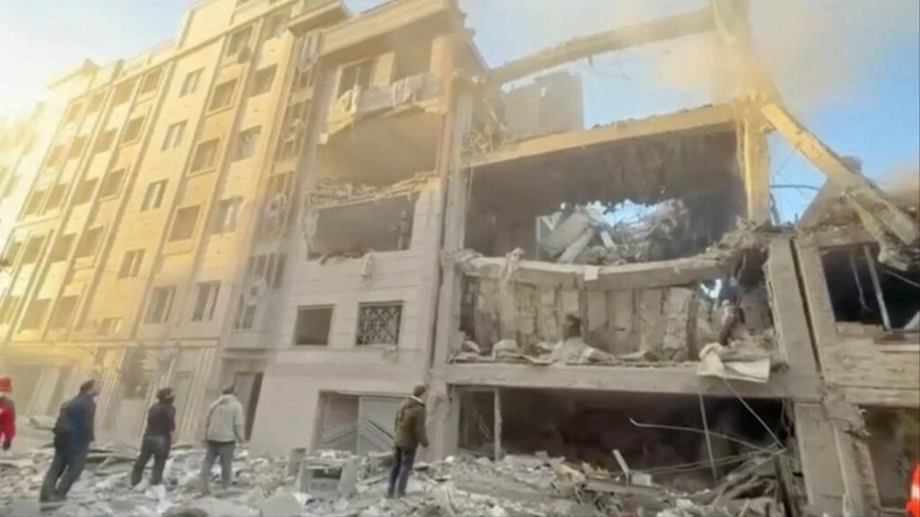 People stand near damaged buildings, amid the U.S.-Israeli conflict with Iran, in Tehran, Iran, in this still image obtained from a handout video released on April 1, 2026. (Iranian Red Crescent Society/Handout via Reuters)