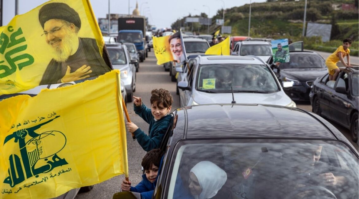 Returnees wave Hezbollah flags bearing pictures of Hasan Nasrallah, the group’s leader killed in the 2024 war, near Ain Abou Abdallah on Friday, April 17, 2026, hours after a cease-fire paused fighting between Israel and Hezbollah. Stuck in standstill traffic, Lebanese people who had been displaced by fighting expressed a mix of excitement and uncertainty about a pause in Israel’s campaign against Hezbollah. (David Guttenfelder/The New York Times)