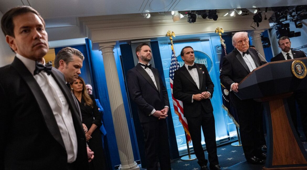Image of Trump administration officials in formal attire standing nearby as President Trump speaks at a podium