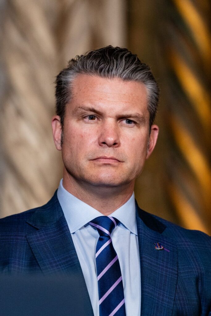 Image of Pete Hegseth in blue suit, blue shirt, with blue and silver striped tie