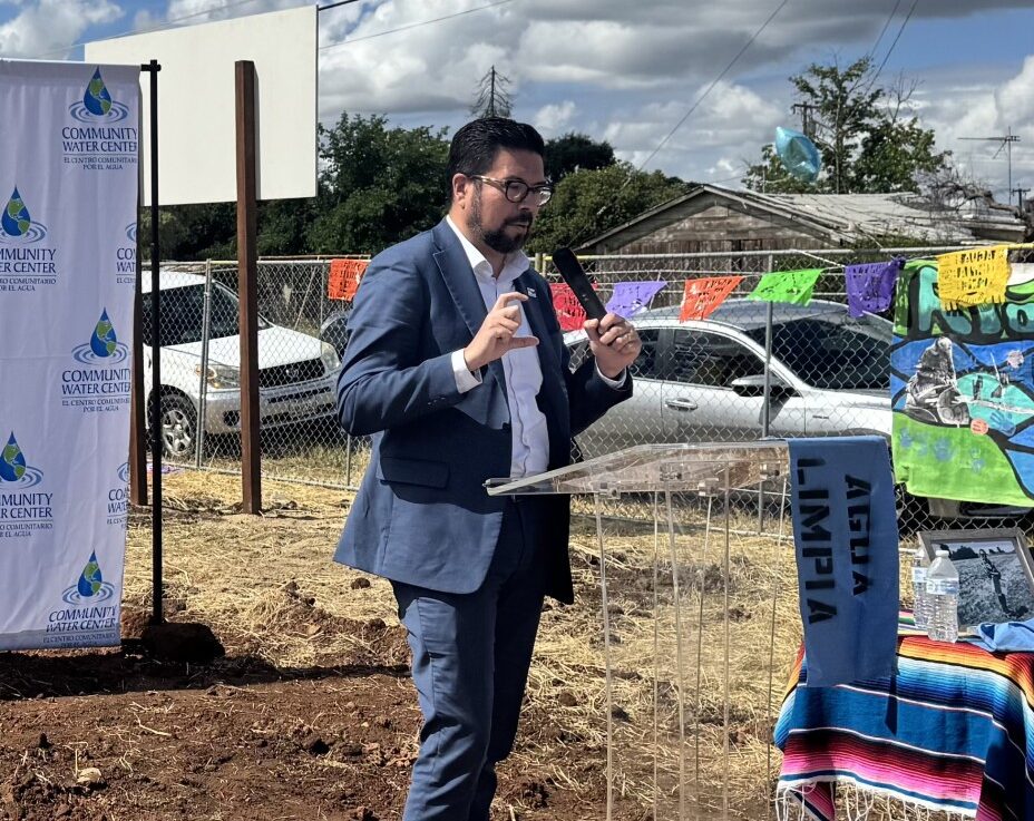 Image of State Water Resources Control Board Chair Joaquin Esquivel, in a blue suit, talking at the East Orosi water system groundbreaking