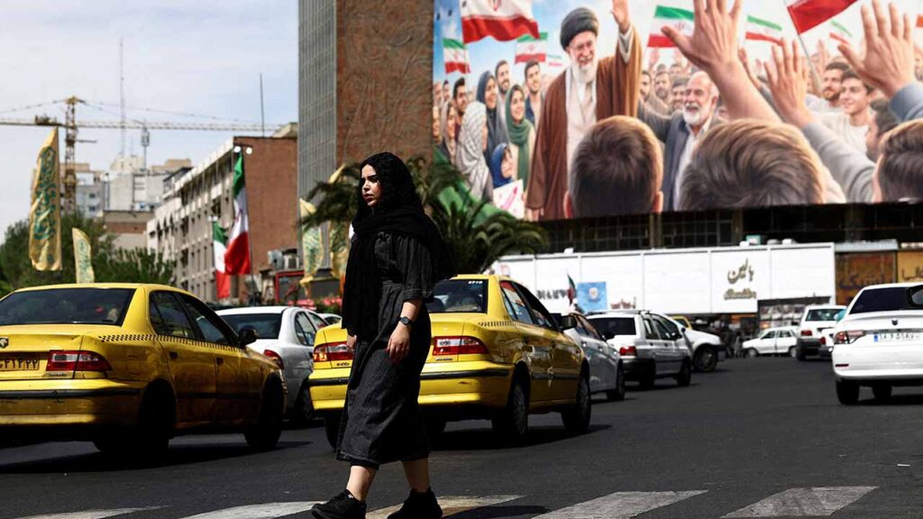 A woman walks past a billboard featuring an image of the late Supreme Leader of Iran, Ayatollah Ali Khamenei, on a building, amid a ceasefire between U.S. and Iran, in Tehran, Iran, April 27, 2026. (Reuters/File Photo)