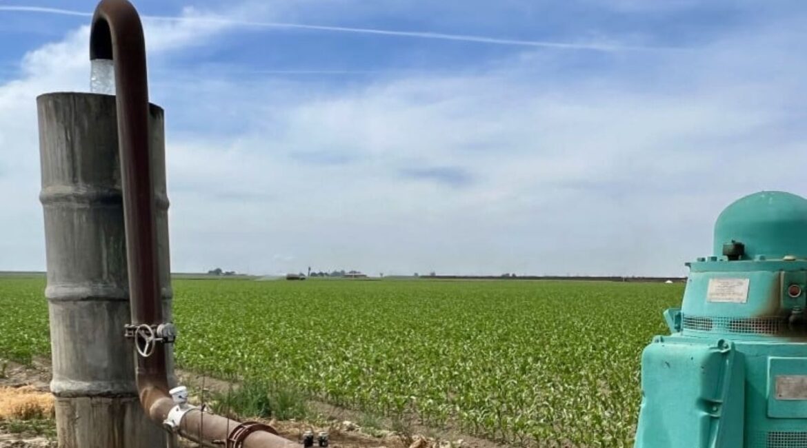 Image of a groundwater well and a nearby standpipe adjacent to a corn field in Tulare County