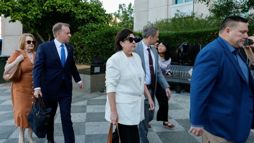Image of Dana Williamson arriving at court. She's wearing a white top and sunglasses s we