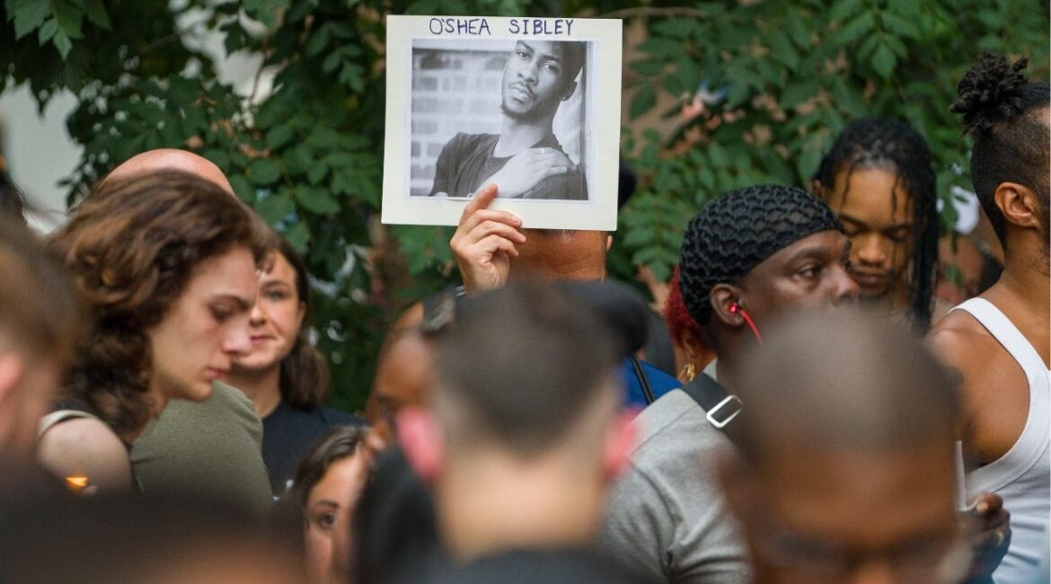 A mourner holds a photo of O’Shae Sible during a memorial and vigil to honor Sibley, a 28-year-old gay man who was fatally stabbed after a dispute over his vogueing in a parking lot, in New York, Aug. 5, 2023. Dmitry Popov was 17 when he stabbed O’Shea Sibley, a 28-year-old dancer, at a gas station on July 29, 2023; he has been charged with murder as a hate crime. (David Dee Delgado/The New York Times)