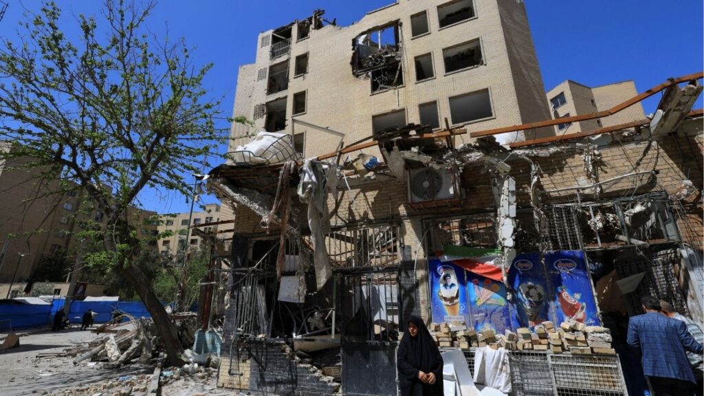 A woman stands next to debris lying in front of a residential building damaged by a strike on March 4, in Tehran, Iran, April 14, 2026. (Reuters File)