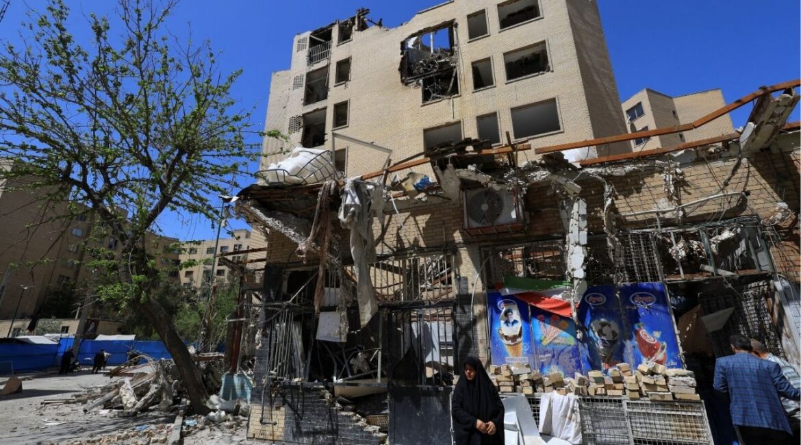 A woman stands next to debris lying in front of a residential building damaged by a strike on March 4, in Tehran, Iran, April 14, 2026. (Reuters File)