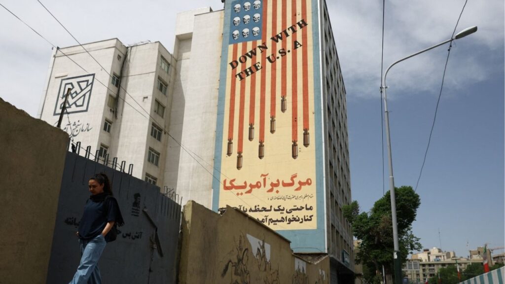 A woman walks past an anti-U.S. mural on a building in Tehran, Iran, May 8, 2026. (Majid Asgaripour/WANA (West Asia News Agency) via Reuters)