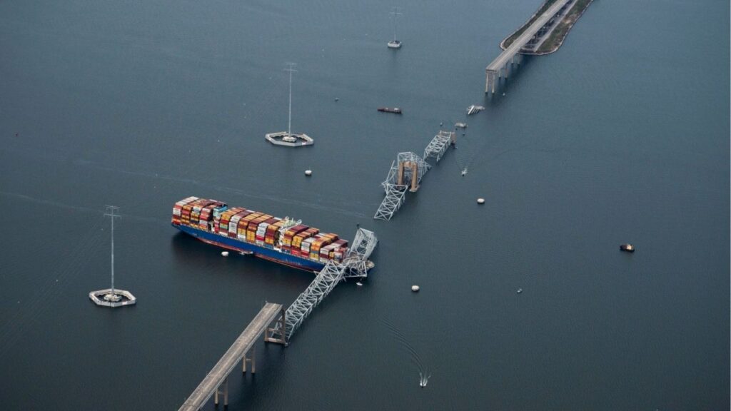 An aerial view of the Dali container ship with a collapsed section of the Francis Scott Key Bridge across its bow, in Baltimore on March 26, 2024. Federal prosecutors announced criminal charges on May 12, 2026 against the owner and operator of the Dali, more than two years after the vessel slammed into the Key Bridge, killing six workers and bringing one of the nation’s busiest ports to a halt. (Erin Schaff/The New York Times)