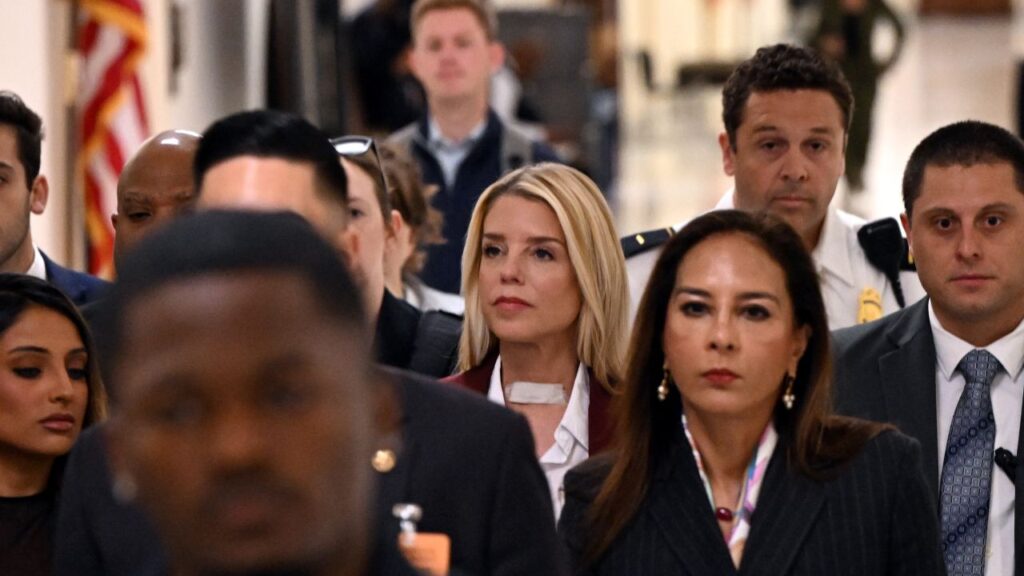 Image of former AG Pam Bondi arriving for a House hearing while surrounded by a crowd of people