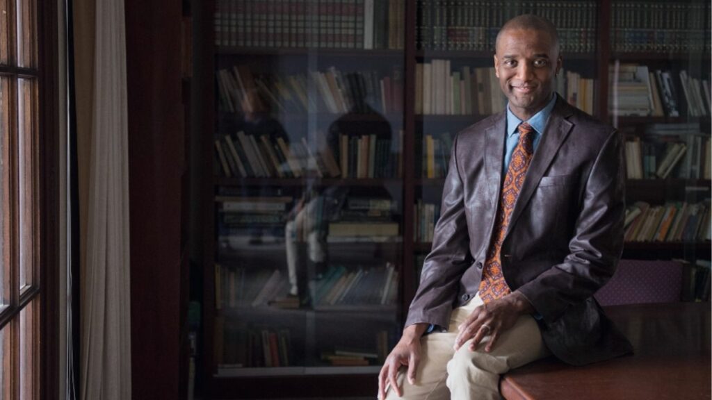 Image of Dr. S. Marshall Perry in a dark library. He's wearing a fashionable suit