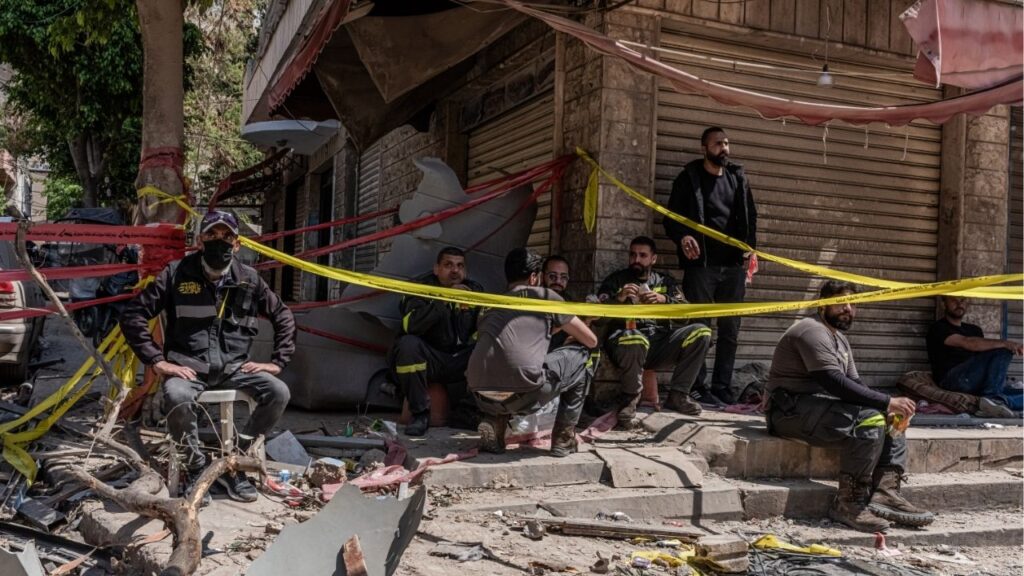 Emergency workers take a break during their search for bodies in the rubble of a building destroyed by an Israeli airstrike in Dahiyeh, a suburb south of Beirut, on Thursday, May 7, 2026. Fighting intensified on Friday between Israel and Hezbollah, the Iran-backed Lebanese militant group, fraying an already fragile cease-fire between them. (Daniel Berehulak/The New York Times)
