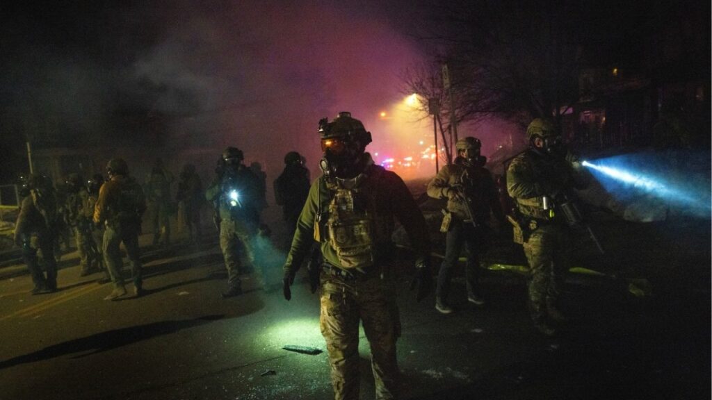 Federal agents face off with protesters in a neighborhood after a federal agent shot a man from Venezuela while attempting to detain him in Minneapolis, Jan. 14, 2026. An Immigration and Customs Enforcement agent charged with assault and filing a false police report about his encounter with a Venezuelan immigrant has been detained in Texas while awaiting an extradition hearing. (David Guttenfelder/The New York Times)