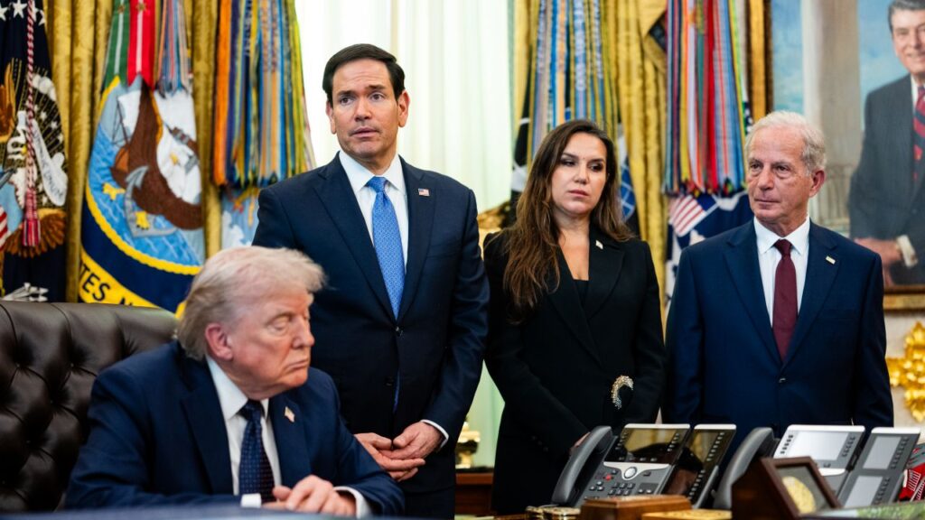 Image of President Trump and Marco Rubio inside the White House. Both are wearing blue suits with American flag lapel pins